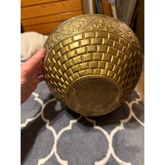 This is a antique brass water vessel, an Indian chambu or lota, featuring intricate etched floral and basket-weave patterns.