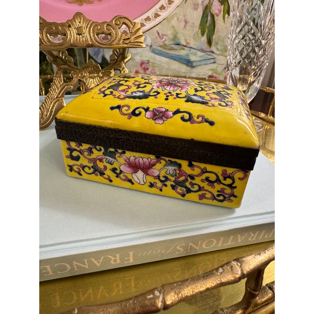A striking chinoiserie porcelain lidded box finished in a richly saturated imperial yellow ground, adorned with finely...