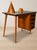 A distinctive mid-century writing desk featuring a rectangular writing surface, four integrated drawers, and slender...