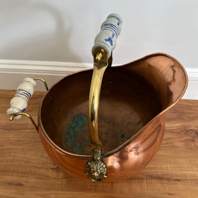 Handsome vintage copper coal scuttle featuring a rounded body, flared pouring edge, pedestal base, and brass swing handle....