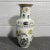 White vase with ducks and garden scenes in tones of blue, yellow, and gold. Accented with a gold rim. Decorated in Hong Kong.