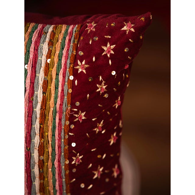 "Infuse vibrance into your space with this deep red cushion, featuring a bold striped panel in earthy tones accented by...