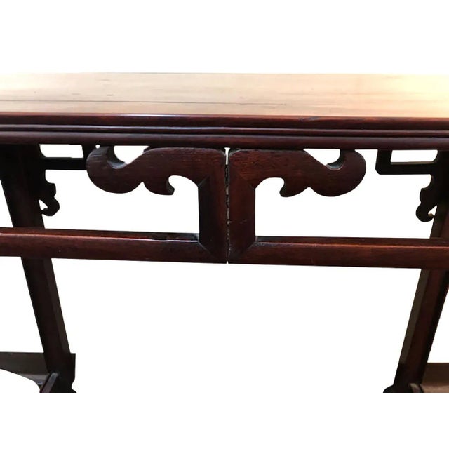A 19th century Chinese carved hardwood table. Possibly Huanghualim with a paneled top and side skirts. Pierced and shaped...