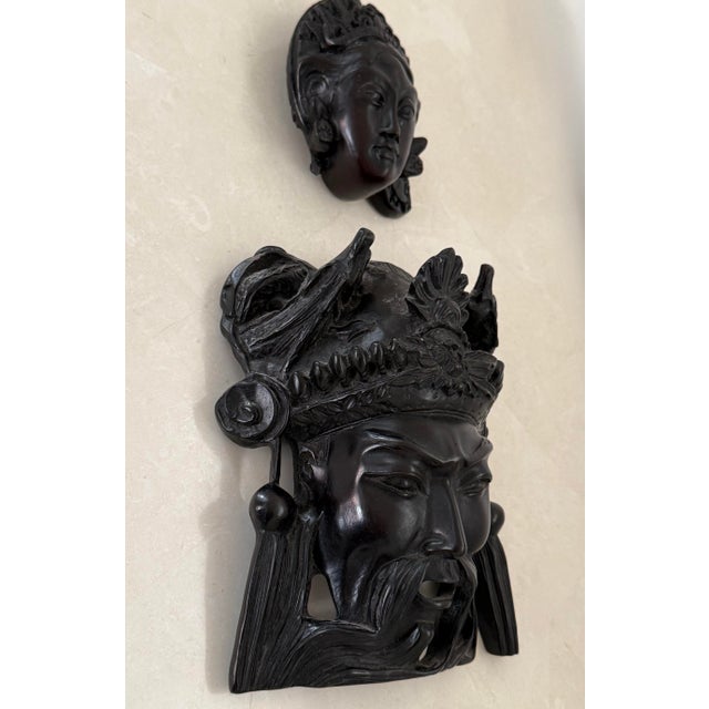 Late 20th century carved wall sculpture pair of an Asian warlord and a queen. Wood is covered in a waxy coating which...