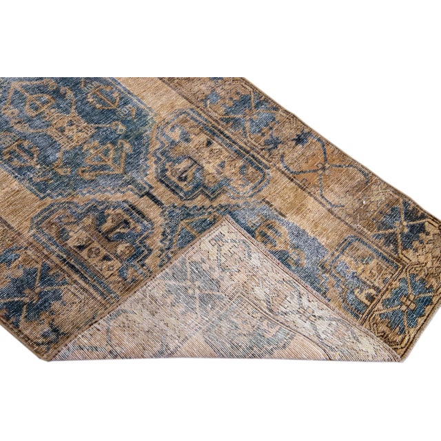 Beautiful vintage Persian distressed hand-knotted wool rug with a brown color field. This piece has a tan frame and navy...