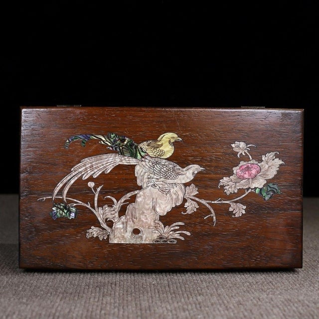 This is a beautifully crafted rectangular wooden box featuring intricate mother-of-pearl (nacre) inlay work on the lid....