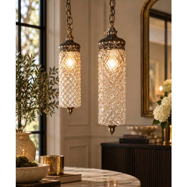 A striking matching pair of vintage Hollywood Regency pendant lights featuring elongated cylindrical clear textured-glass...