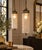 A striking matching pair of vintage Hollywood Regency pendant lights featuring elongated cylindrical clear textured-glass...