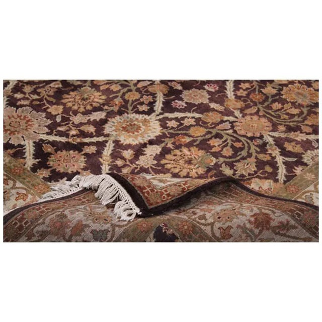 Handwoven Indian rug featuring an Agra design with an aubergine background and ivory-colored border, accented with shades...