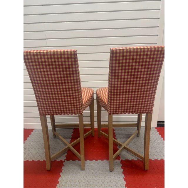 Elegant pair of authentic Donghia upholstered stools from the John Hutton design era. These stools feature a refined wood...