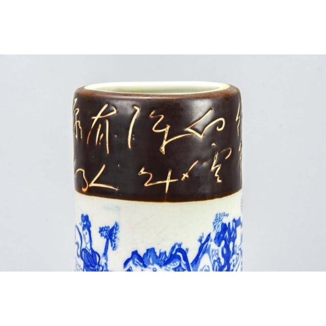 A Chinese porcelain brush pot or vase with blue and white decoration depicting traditional figures and landscape scenes in...