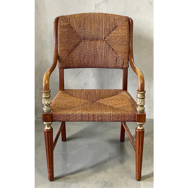 Elegant vintage accent armchair featuring sculptural bent rattan arms, a hand-woven rush seat and back, and a carved wood...