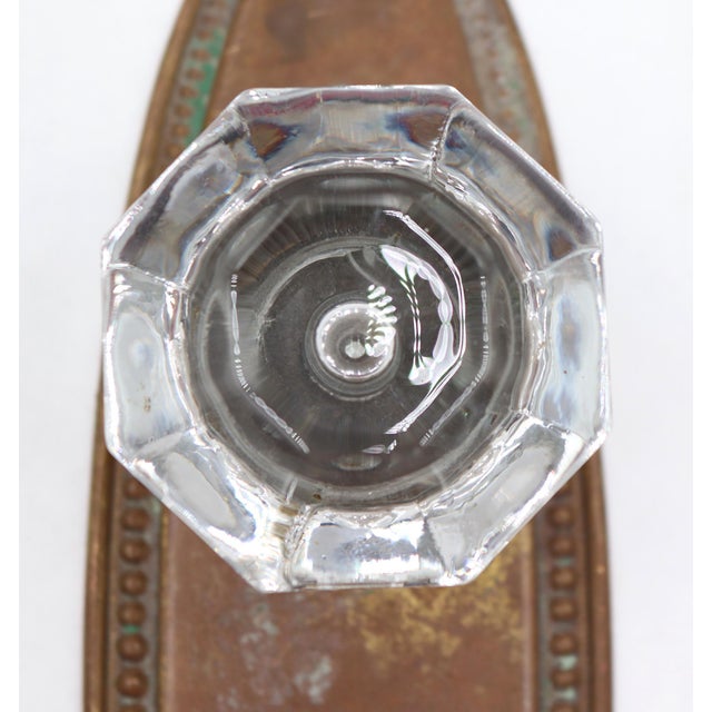 Traditional style dummy door set with an octagonal glass knob on an oval shaped brass back plate with beaded edging. The...