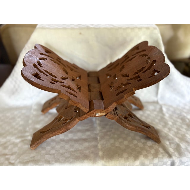 An ornate hand carved book stand featuring a floral and leaf scroll design and made of mango wood. The piece, made in...