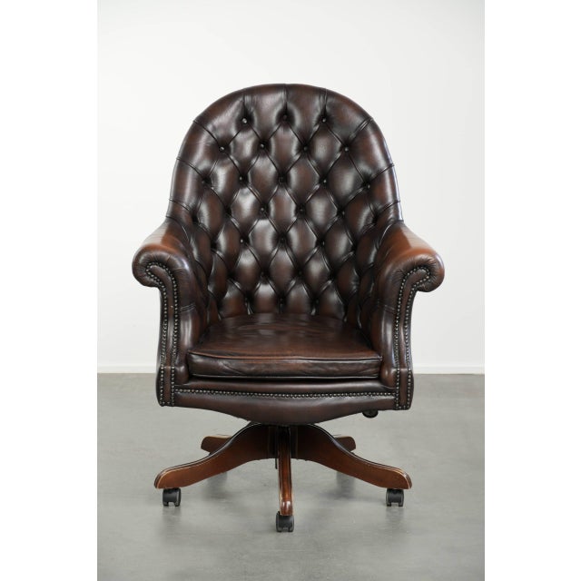 This beautiful old brown cowhide Chesterfield office chair on wheels is in a luxurious English style. It stands on wheels...