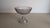 A charming vintage pressed glass compote bowl featuring an elegant pedestal base and a scalloped rim. The bowl showcases...