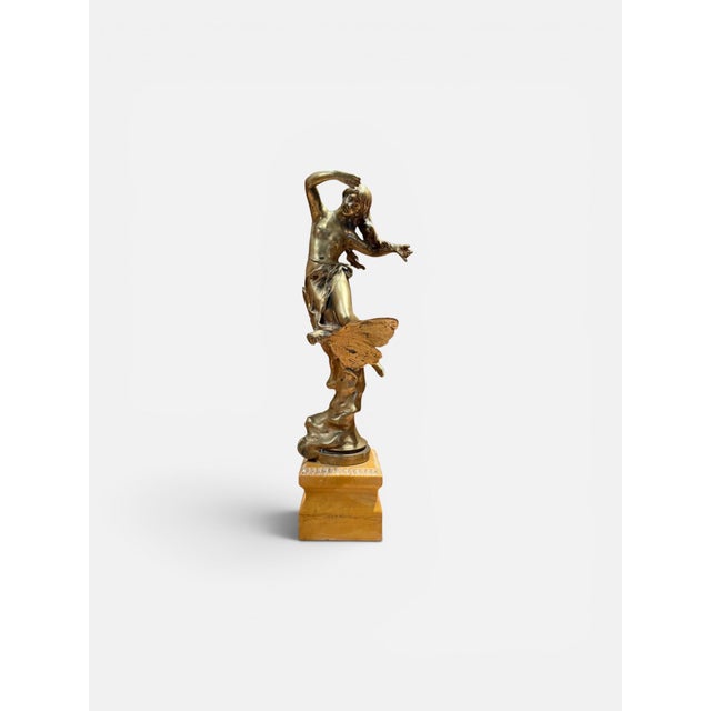 A signed French Art Nouveau figural sculpture depicting a nude female figure in a graceful, dynamic pose, set on a sienna...