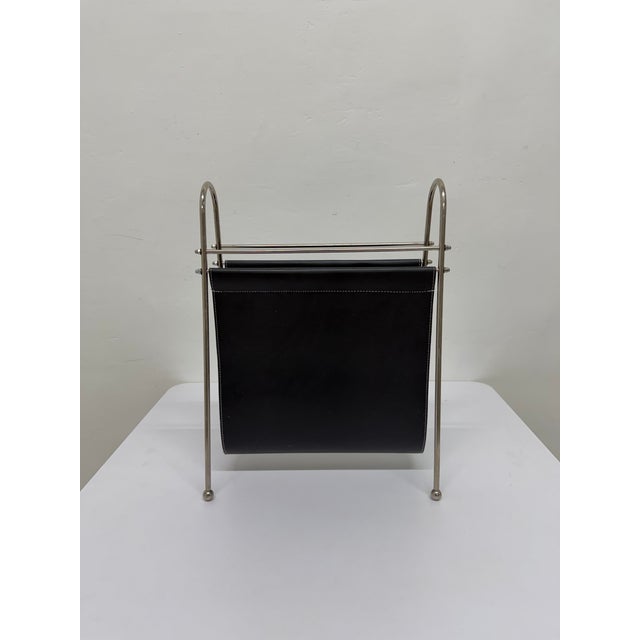 Mid-Century magazine rack with leather sling magazine holder attached to a bent steel frame.