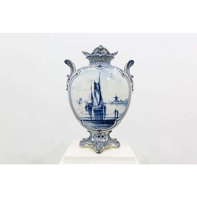 White glazed ceramic vase with Delft blue painted decoration. Flat globular body with two handles in the mouth and four...