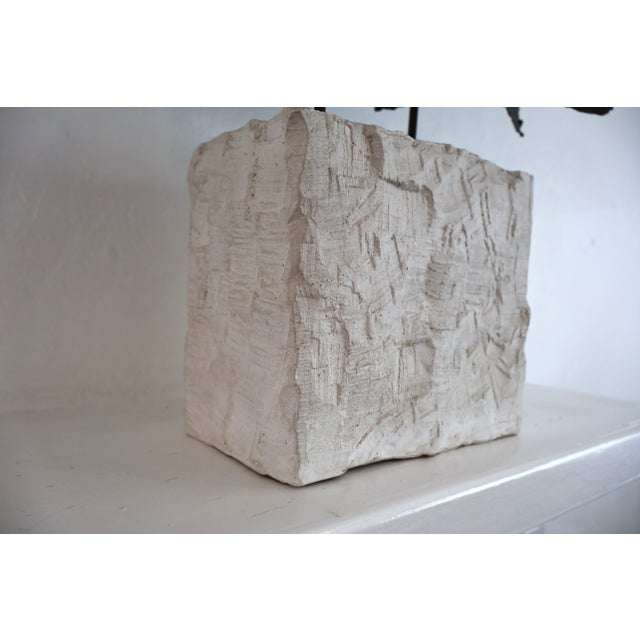 A bold Brutalist tabletop sculpture in torch-cut metal, rising from a rough plaster base. The jagged, molten edges and...