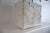 A bold Brutalist tabletop sculpture in torch-cut metal, rising from a rough plaster base. The jagged, molten edges and...