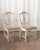 A well-composed set of seven Swedish Gustavian-style dining chairs in antique white painted frames with velour upholstered...