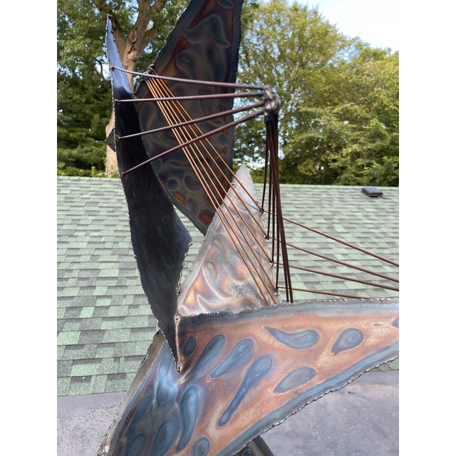 A large abstract brutalist sculpture with triangular torch cut steel panels and metal rods attached to a removable longer...