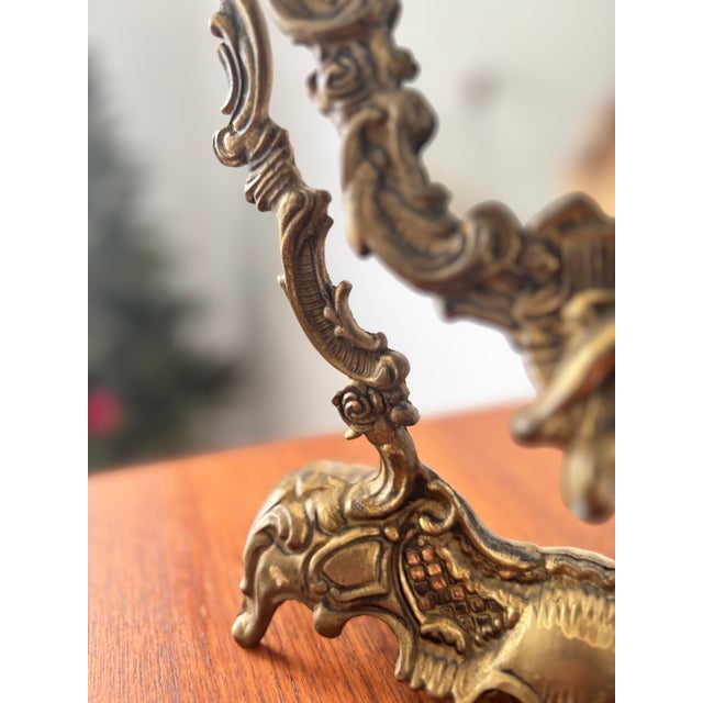 Stunning antique table mirror in patinated brass-colored metal, richly adorned with Baroque motifs and cherubs. This...
