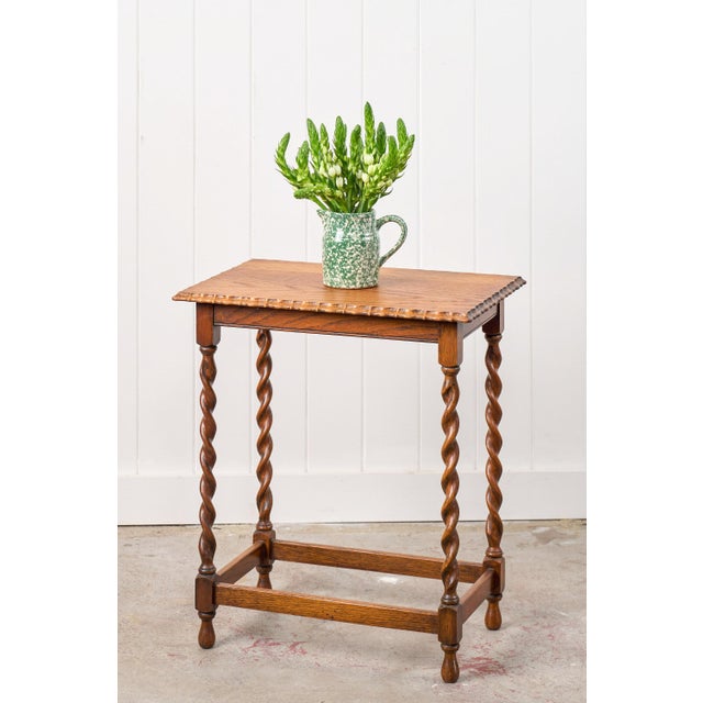 This antique English rectangle barley twist table features honey oak and a scalloped top. The four barley twist turned...