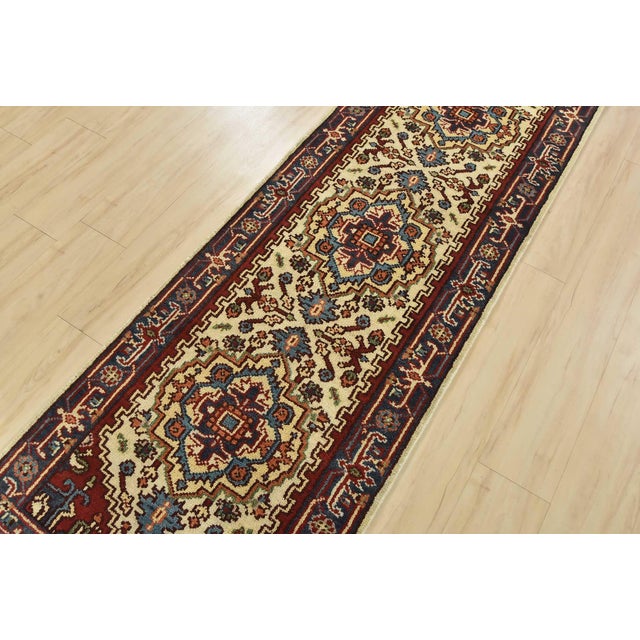 A traditional tribal Heriz runner hand-knotted with an all-wool pile on a cotton foundation. This oriental rug features a...