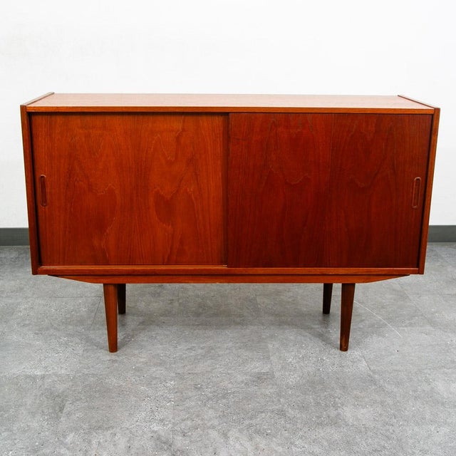 Teak compact sliding door credenza on 4 tapered legs. Recently imported from Denmark. Unstamped example.