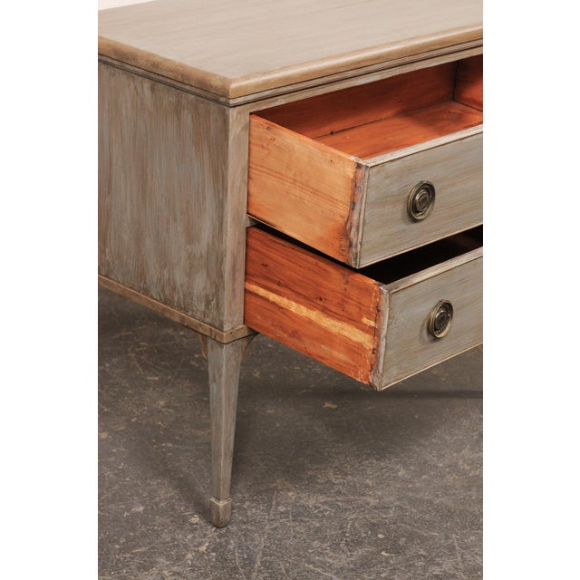 A French smaller-sized, painted wood, raised chest of two drawers from the 19th century. This antique commode from France,...