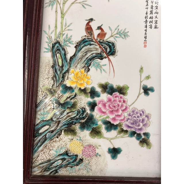 This ceramic wall hanging features birds perched on a ledge and flowers in the foreground and bamboo in the backround....