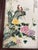 This ceramic wall hanging features birds perched on a ledge and flowers in the foreground and bamboo in the backround....