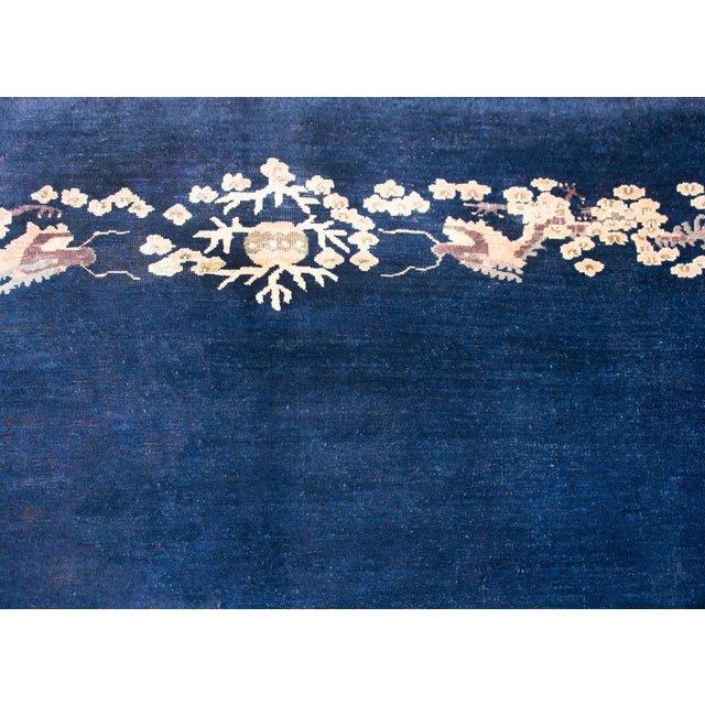 A stunning early 20th century Chinese Peking rug with a rich dark indigo field surrounded by a border of mirrored repeated...