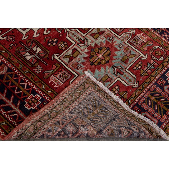 Beautiful vintage Persian Heriz hand-knotted wool runner with a red field. This Persian rug has a navy blue frame and...