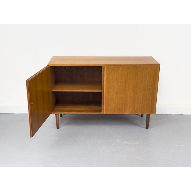 Teak sideboard with two handleless cabinet doors featuring solid wood edges. Beautiful grain and high-quality...