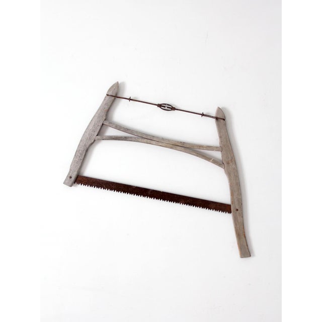 Early 20th-century wooden buck saw with a hand-built frame, iron tension rod, and aged crosscut blade. The curved...