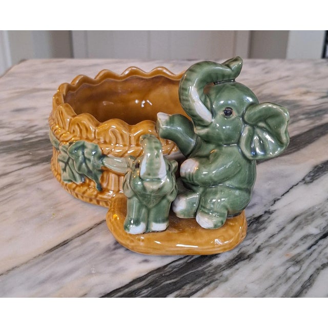 Auspicious by nature, this majolica style painted and glazed planter features a mother and child elephant pair with trunks...