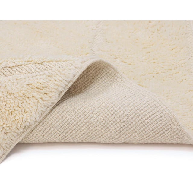 Elegant hand-knotted Ivory rug showcasing a delicate diamond pattern, offering a soft, luxurious texture that complements...