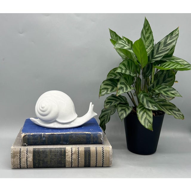 Playful and sculptural ceramic snail in a glossy white finish. With its exaggerated spiral shell and stylized antennae,...