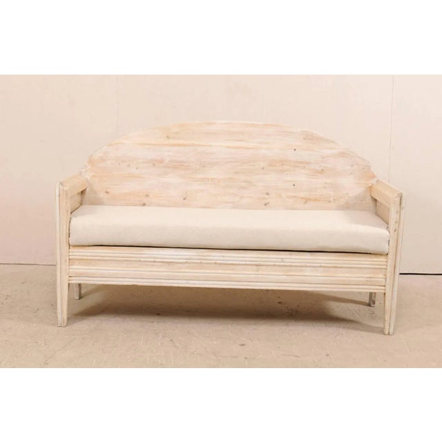A Swedish sofa bench from the early 19th century. This antique Swedish wood sofa bench features a nicely arched back with...