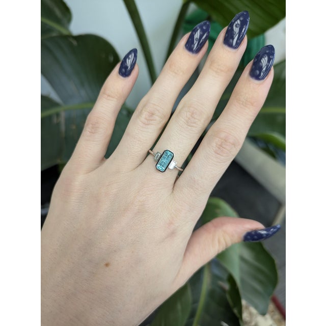 A rare Paraiba color tourmaline takes centre stage in an electric blue-green at the heart of this solid 14K white gold...