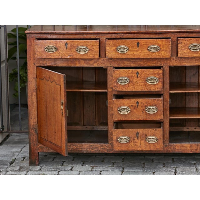 An English oak buffet from the 19th century with six drawers, two doors and brass hardware. This 19th-century English oak...
