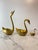 Set of three vintage brass swan figurines featuring elegant, sculptural forms and a warm golden patina. Each swan is...