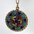 An 18 karat (18K) yellow gold charm pendant designed as a round medal with a rope-twist edge depicting a stained glass...