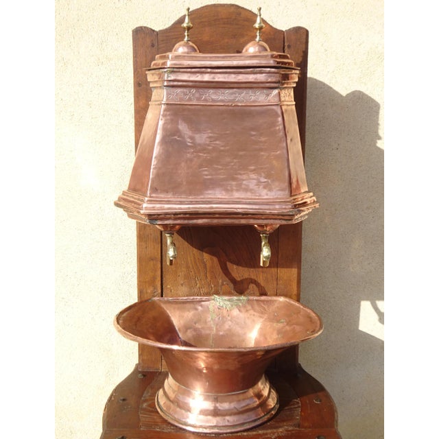 A very old, complete copper fountain, comprising a reservoir with a lid and two taps, a basin, and a large solid oak...