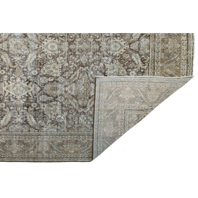 Elevate your interior with this exceptional antique Mahal rug, featuring a sophisticated palette of deep mocha, muted...