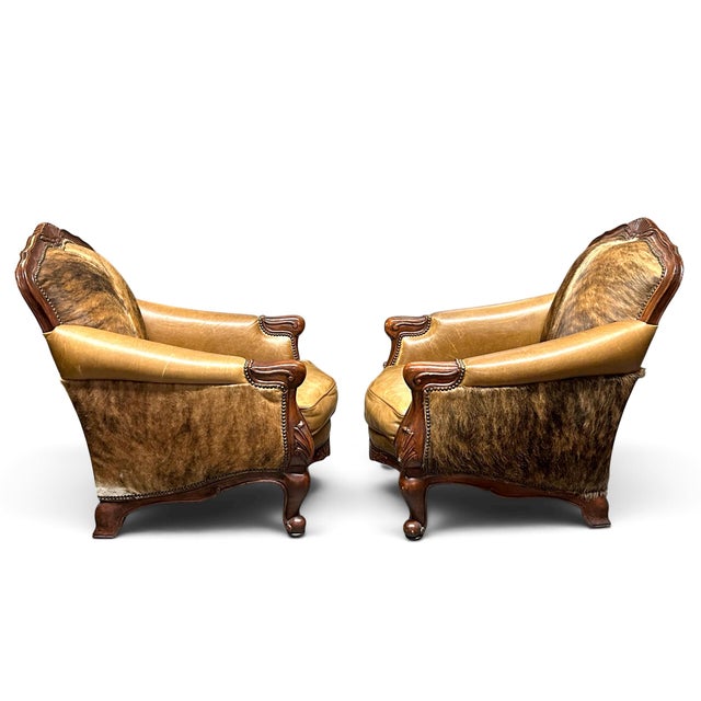 Pair of stunning cowhide and leather armchairs trimmed with a brass nailhead design from Creative Leather Furniture. Super...