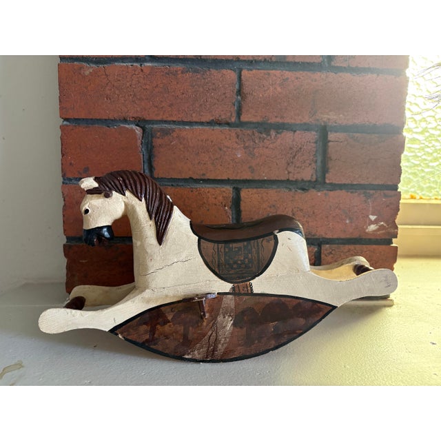 Charming vintage wooden rocking horse featuring a hand-painted finish in warm brown and cream tones. The piece reflects a...